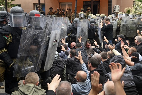 epaselect epa10662176 Ethnic Serbs sit on the street in front of the cordon of soldiers of NATO-led international peacekeeping Kosovo Force (KFOR) in front of the building of the municipality in Zveca ...