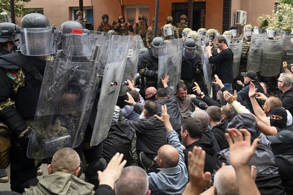 epaselect epa10662176 Ethnic Serbs sit on the street in front of the cordon of soldiers of NATO-led international peacekeeping Kosovo Force (KFOR) in front of the building of the municipality in Zveca ...