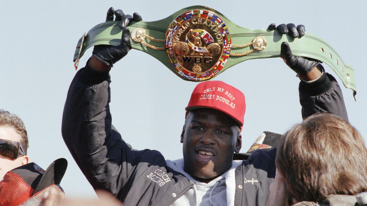 James "Buster" Douglas holds the WBC heavyweight championship belt over his head as he greets Monday, Feb. 12, 1990 by more than 1,000 fans at the Columbus airport. Douglas knocked out Mike  ...