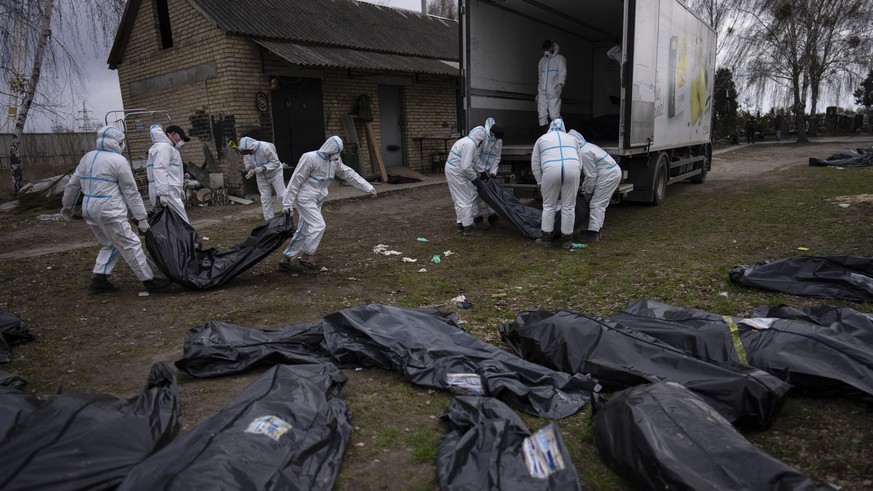 FILE - Volunteers load bodies of civilians killed in Bucha onto a truck to be taken to a morgue for investigation, in the outskirts of Kyiv, Ukraine, Tuesday, April 12, 2022. Russian soldiers in inter ...