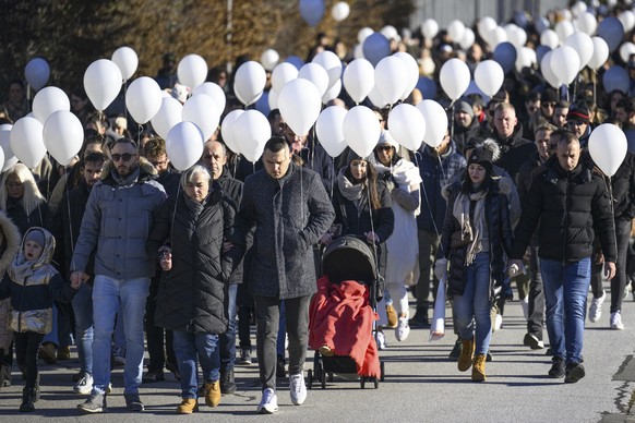 People carry white balloons as they take part of a &quot;Marche Blanche&quot; (White March) to pay tribute to the victims of the 11 December shooting, in Sion, Switzerland, Saturday, Dec. 16, 2023. Tw ...