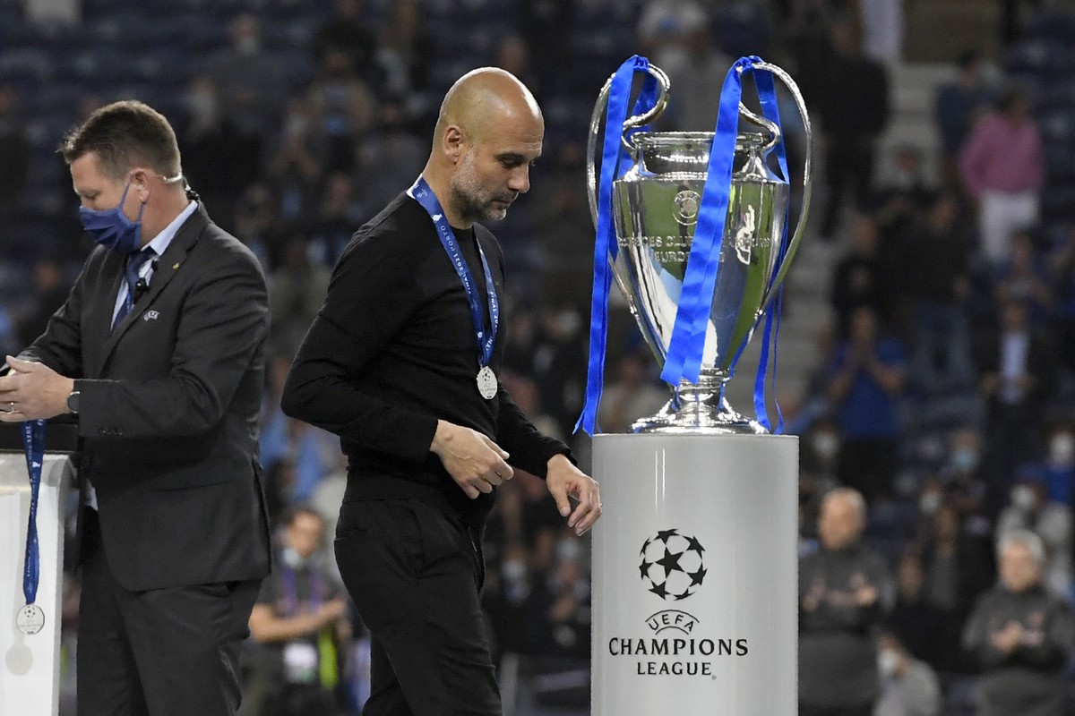 Manchester City's head coach Pep Guardiola walks past the trophy at the end of the Champions League final soccer match between Manchester City and Chelsea at the Dragao Stadium in Porto, Portugal ...