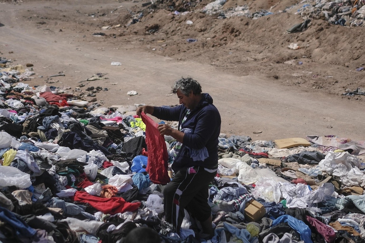 Alexis Carreno looks through a large pile of second-hand clothing near La Mula neighborhood in Alto Hospicio, Chile, Monday, Dec. 13, 2021. Chile is a big importer of second hand clothing, and unsold  ...