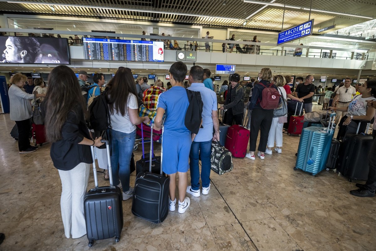 Des passagers arrivent avec leurs bagages a l'Aeroport International de Geneve, ce samedi 9 juillet 2022 a Geneve. L'aeroport fait face a un fort trafic local de departs de vacances d?ete, u ...