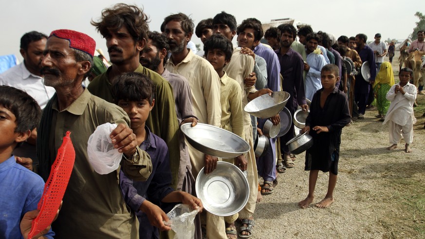 Flood affected people stand in a long line with utensils to get food distributed by Pakistani Army troops in a flood-hit area in Rajanpur, district of Punjab, Pakistan, Saturday, Aug. 27, 2022. Offici ...