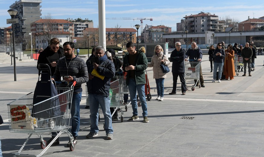 epa08278137 Consumers wait in long lines to go shopping at a supermarket due to restrictive quotas for entry, in San Donato Milanese, near Milan, northern Italy, 08 March 2020. The Italian authorities ...