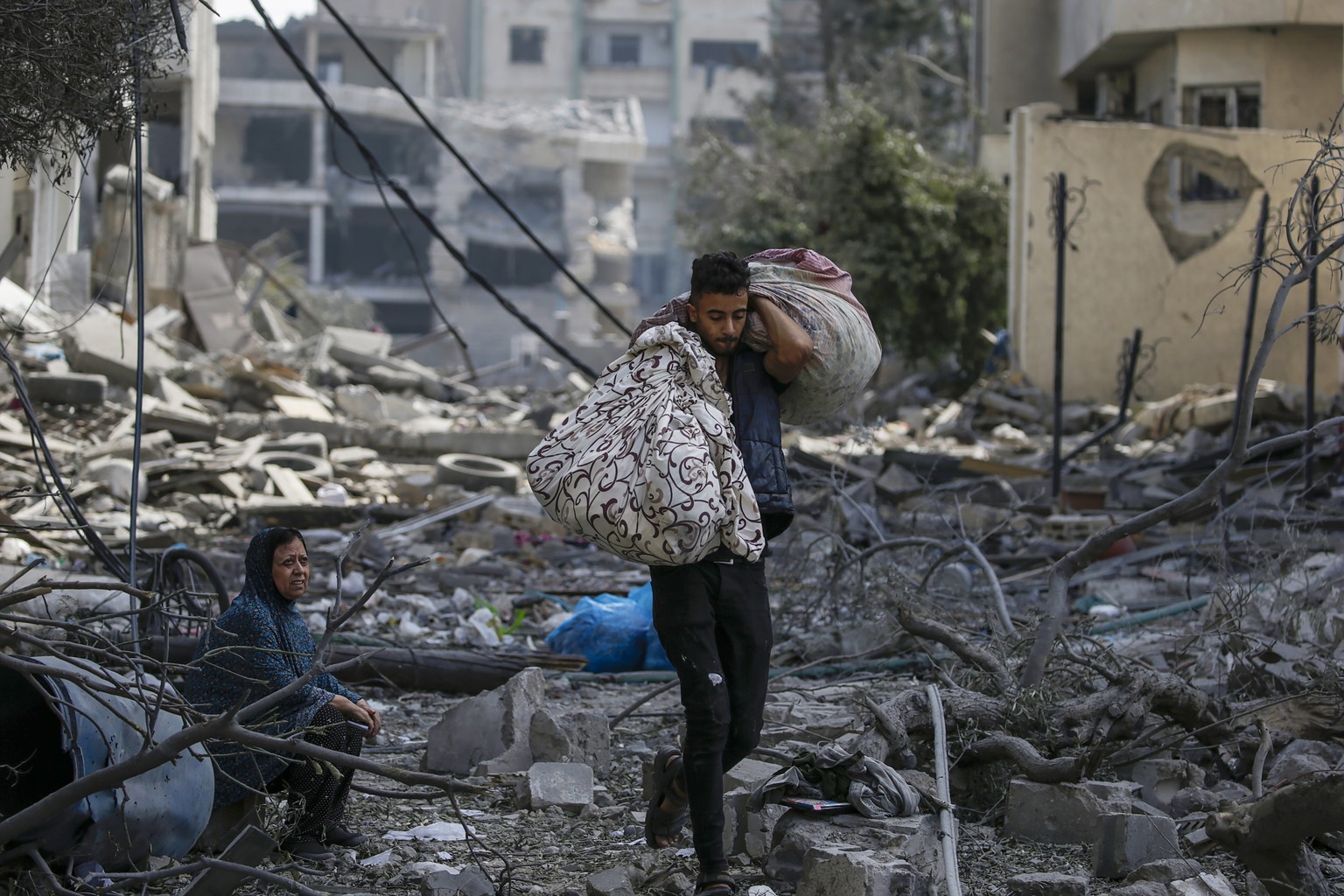 epa10911537 A Palestinian woman (L) sits among the rubble in the destroyed Al-Ramal neighborhood following an Israeli air strike in Gaza City, 10 October 2023. More than 700 people have been killed an ...