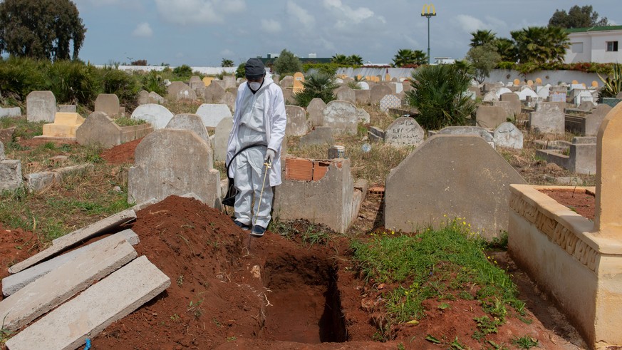 epa08327044 People spray disinfectants during the burial of one of the victims who died from Covid-19 in Rabat, Morocco, 27 March 2020. According to reports, Morocco has confirmed 275 cases of the COV ...