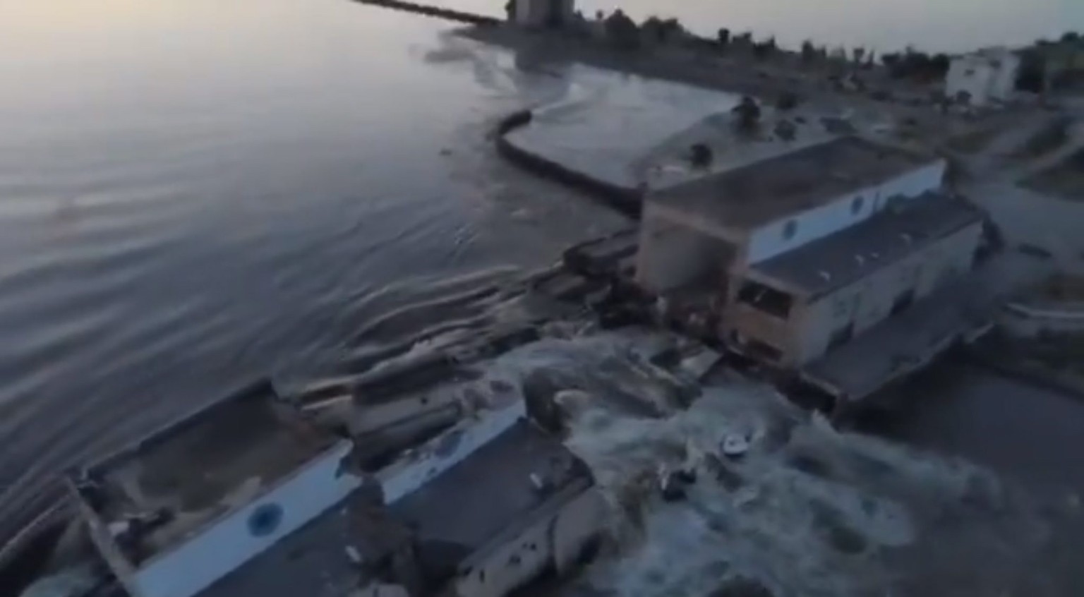 epa10675811 A still image from a handout video made available by the telegram account of the President of Ukraine Volodymyr Zelensky on June 6, 2023, of water flowing through a breach in the…