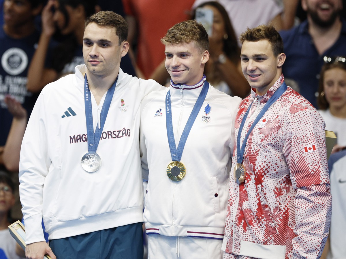 epa11513649 (L-R) Silver medalist Kristof Milak of Hungary, gold medalist Leon Marchand of France, and bronze medalist Ilya Kharun of Canada pose on the podium for the Men 200m Butterfly final of the  ...