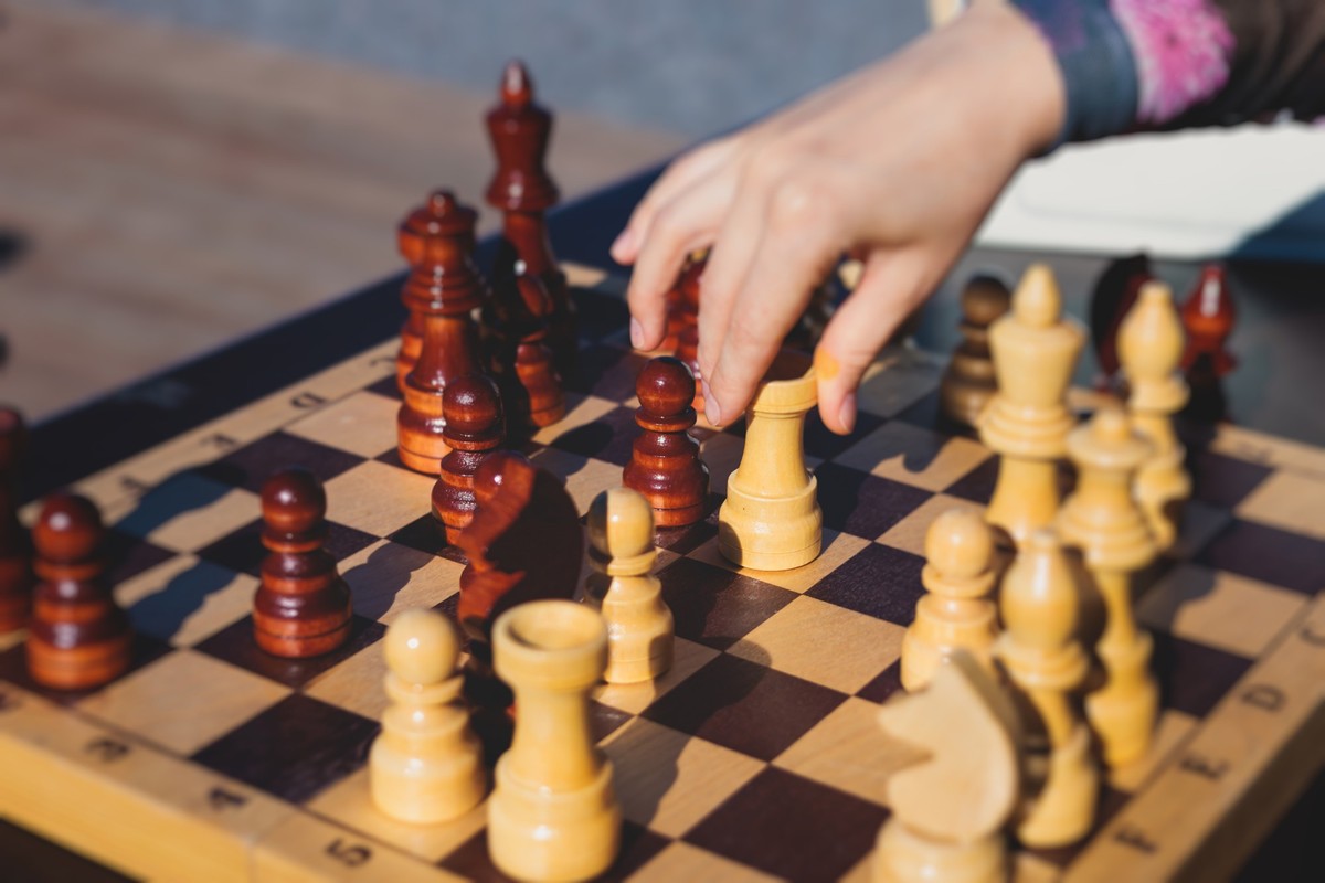 Chess tournament, kids and adults participate in chess match game outdoors in a summer sunny day, players of all ages play, competition in chess school club with chessboards on table