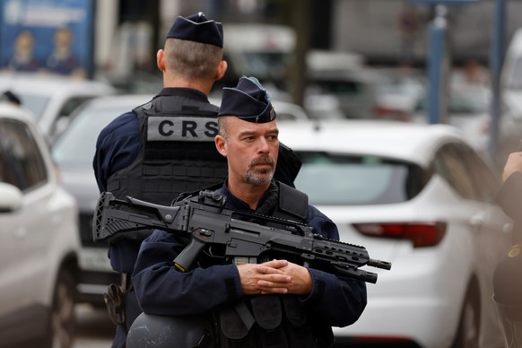 epa10917176 A police officer holds an HK G36 assault rifle as he stands guard near the Gambetta high school in Arras, northeastern France, 13 October 2023, after a teacher was killed and two other peo ...