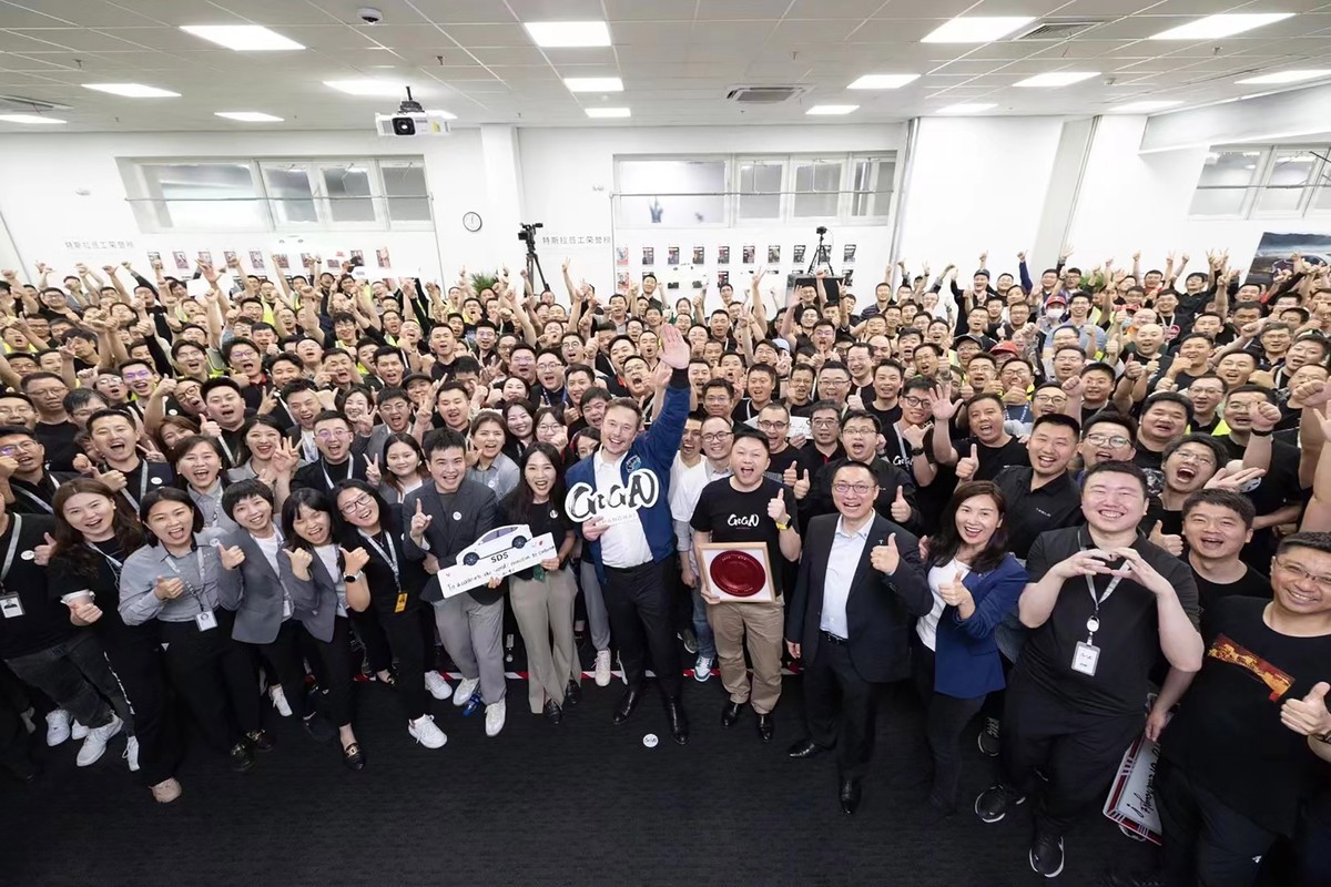 epa10666595 A handout photo made available by Tesla, Inc. shows Tesla CEO Elon Musk (front C) posing for a group photo with his employees at the auto maker's Shanghai factory, in Shanghai, China, ...