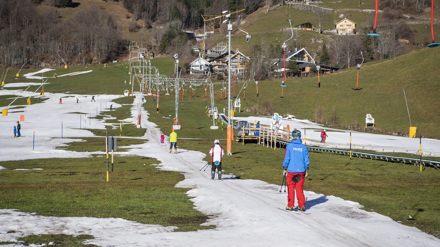 Skifahrer vergnuegen sich auf der Kunstschneepiste der Klostermatte in gruener Landschaft, aufgenommen am Samstag, 7. Januar 2023, in Engelberg im Kanton Obwalden. (KEYSTONE/Urs Flueeler). People enjo ...