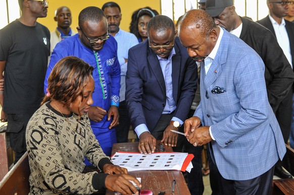 epa10821770 Gabonese President Ali Bongo Ondimba (R), speaks with an election official after casting his vote during the 2023 Gabonese general elections in Libreville, Gabon, 26 August 2023. A little  ...