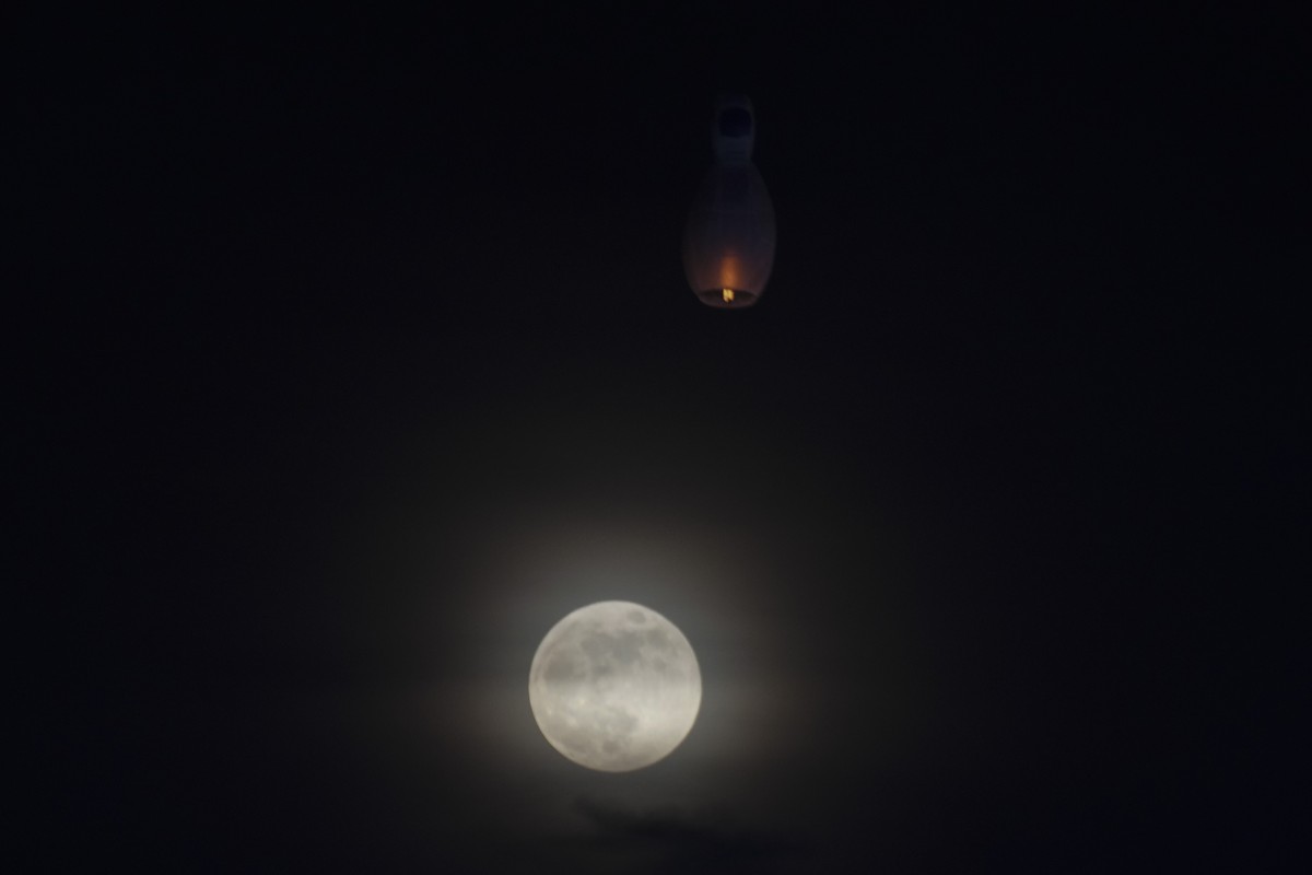 A supermoon rises while a hot-air balloon fly during the full moon day of Thadingyut, the end of Buddhist Lent, Thursday, Oct. 17, 2024, in Yangon, Myanmar. (AP Photo/Thein Zaw)