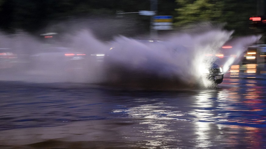 epa06056938 A car splashes water as it drives through floodwater in Berlin, Germany, 29 June 2017. Heavy rainfall hit Berlin late 29 June that lead the firebrigade to declard a state of emergency. EPA ...