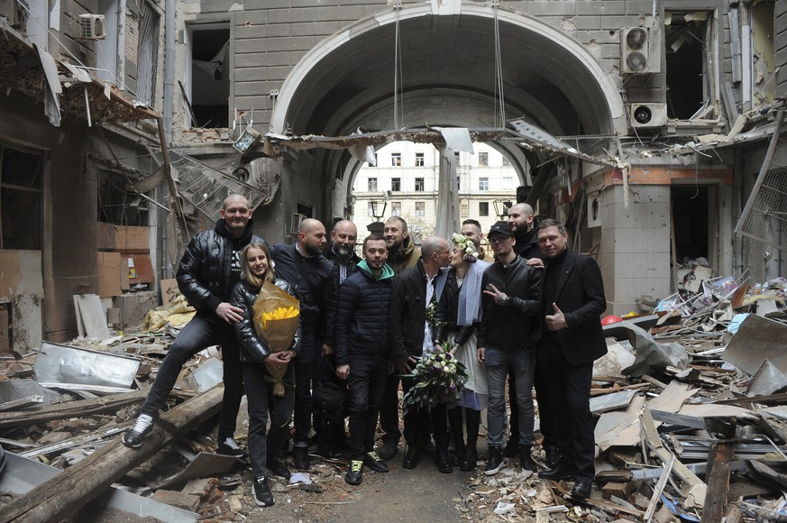 Volunteers Anastasia, third from left, and Anton pose for a picture with their friends in a yard of a destroyed by shelling apartment building during their wedding celebration in Kharkiv, Ukraine, Sun ...