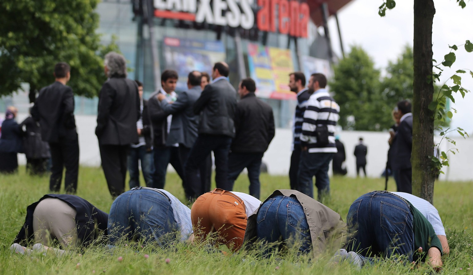 Anhänger von Erdogan stehen vor der Lanxess-Arena, während andere beten.&nbsp;