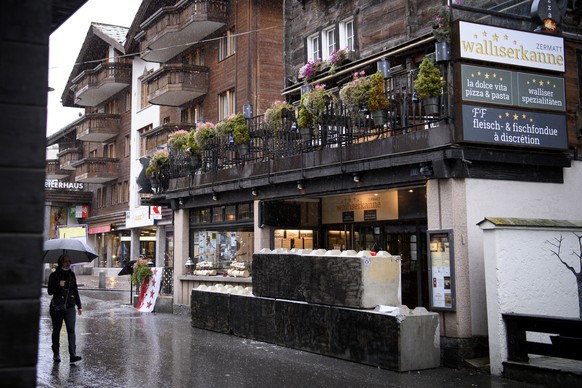 Peoples pass in front of concrete blocks blocked the entrance of the restaurant &quot;Walliserkanne&quot; after the restaurant was closed and the owners were arrested by the police for not respecting  ...