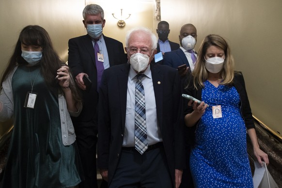 epa09493953 Independent Senator from Vermont Bernie Sanders (C) is followed by members of the news media on Capitol Hill in Washington, DC, USA, 28 September 2021. The Senate faces a 30 September dead ...