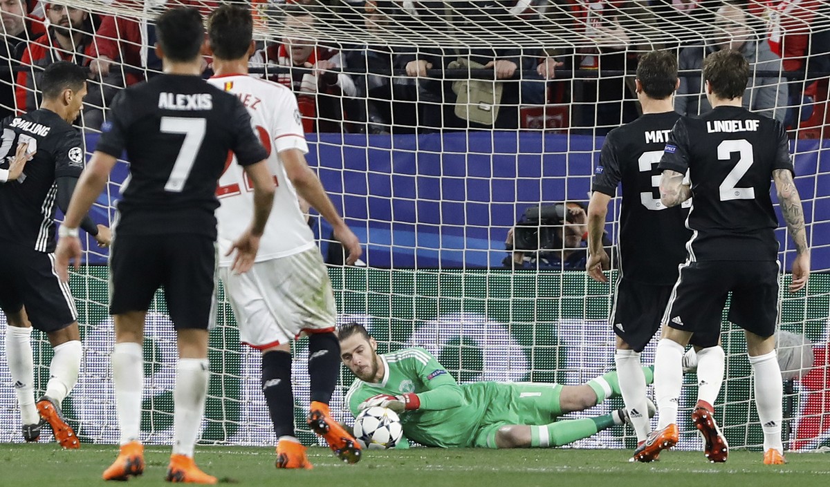 Manchester United goalkeeper David de Gea, center, dives for a save during the Champions League round of sixteen first leg soccer match between Sevilla FC and Manchester United at the Ramon Sanchez Pi ...