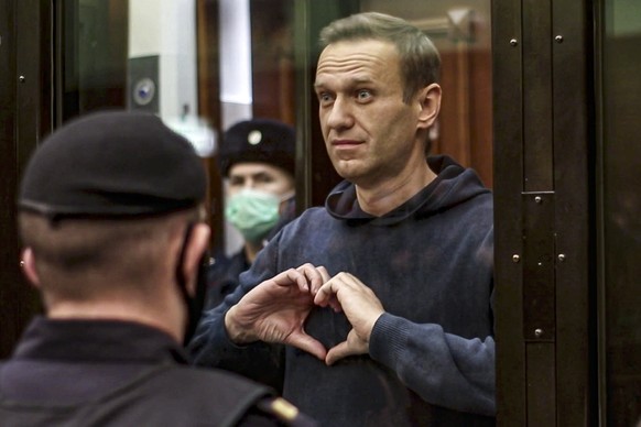 FILE - In this handout photo taken from a video from the Moscow District Court on February 2, 2021, Russian opposition leader Alexei Navalny shows a heart symbol while standing in a defendant's cage...