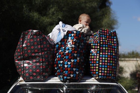 A Syrian kid fleeing the war in Lebanon with his family, sits on the top of car between belongings, at the Syrian-Lebanese border crossing in Jousieh, Syria, Tuesday, Oct. 2, 2024. (AP Photo/Omar Sana ...