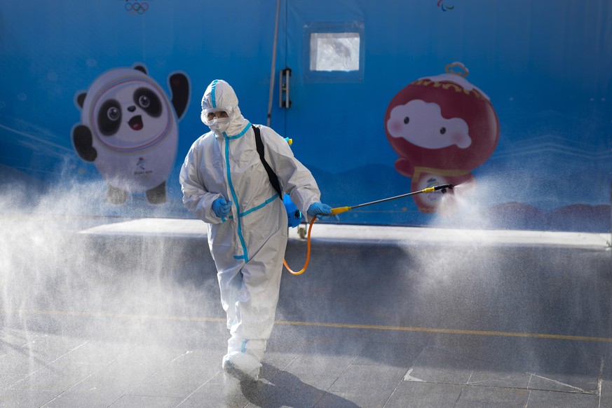 A worker wearing a protective suit sprays disinfectant outside an hotel at the 2022 Winter Olympics, Feb. 3, 2022, in Beijing. (AP Photo/Natacha Pisarenko)