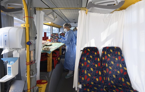 Medical staff prepare a bus, containing a so-called rolling vaccination center, for a the test run in Grosshartmannsdorf, Germany, Sunday, Feb. 21, 2021. Mobile vaccination centers will be used to vac ...