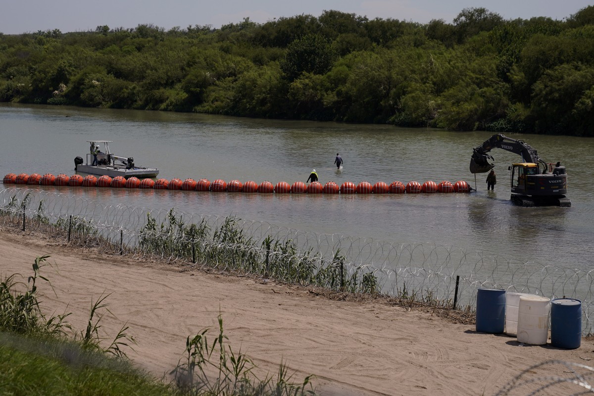 Workers deploy a string of large buoys to be used as a border barrier at the center of the Rio Grande near Eagle Pass, Texas, Tuesday, July 11, 2023. The floating barrier is being deployed in an effor ...