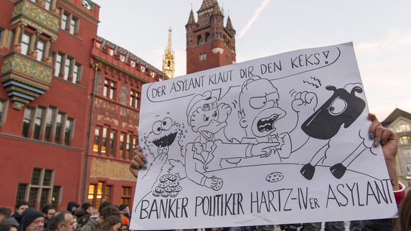 Eine Frau haelt ein Plakat mit der Aufschrift &quot; Der Asylant klaut Dir den Keks!&quot; auf dem Marktplatz vor dem Rathaus in Basel, am Mittwoch, 3. Februar 2016. Zuvor hatte die Kantonspolizei Bas ...