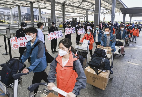 In this photo released by China&#039;s Xinhua News Agency, members of a COVID-19 testing team are greeted at an airport in Shanghai, China, as they prepare to return home to Hubei Province, Saturday,  ...