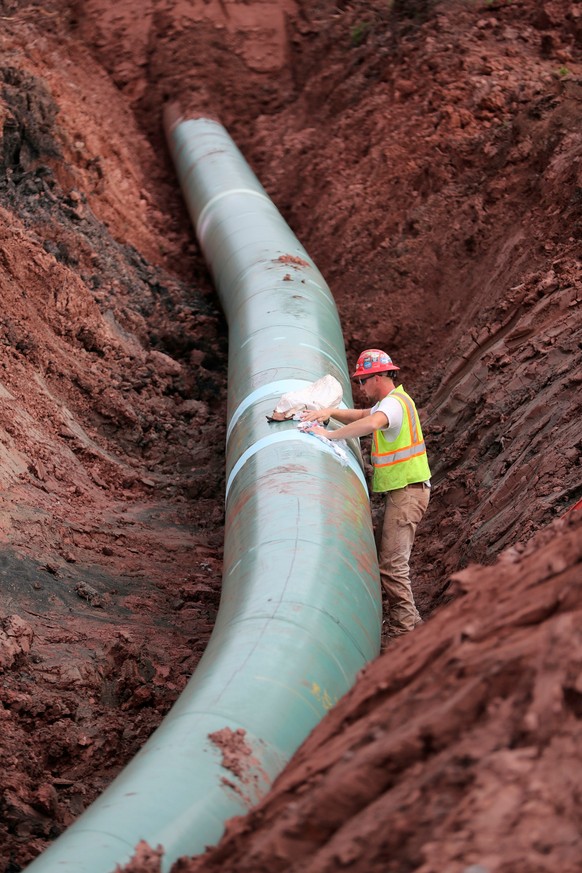 FILE - In this Aug. 21, 2017, file photo, a pipe fitter lays the finishing touches to the replacement of Enbridge Energy's Line 3 crude oil pipeline stretch in Superior, Wisc. After President Joe Bide ...