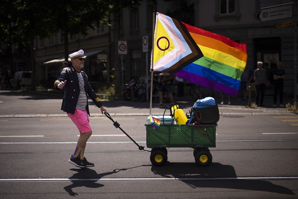 epa10696710 A man carries a wagon with a rainbow flag during the Zurich Pride parade in Zurich, Switzerland, 17 June 2023. EPA/MICHAEL BUHOLZER