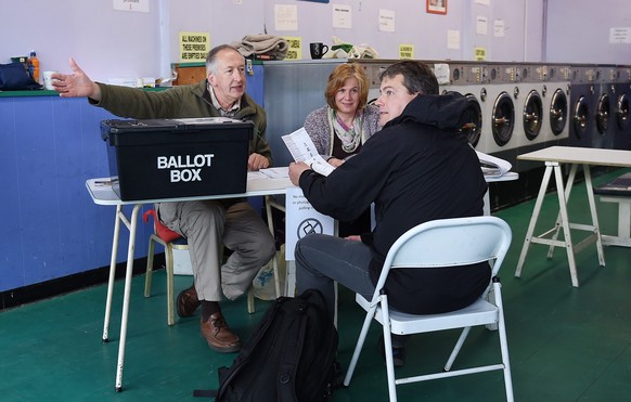 epa04736727 An electoral official talks to a voter at a launderette polling station in Oxford, Britain, 07 May 2015. Britons are voting in a general election which will determine the next Prime Minist ...