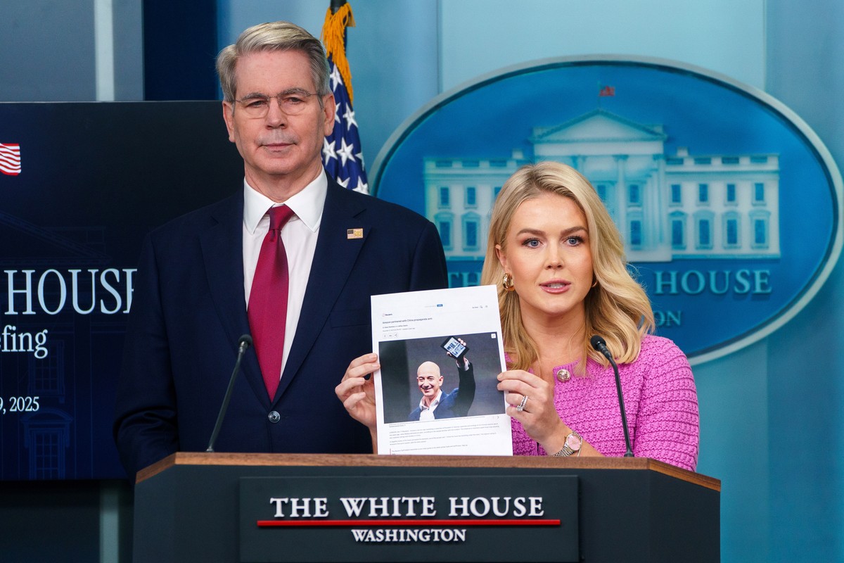 epaselect epa12062562 White House Press Secretary Karoline Leavitt (C) holds a photograph of Amazon founder Jeff Bezos with US Treasury Secretary Scott Bessent (L) during a press briefing at the White ...