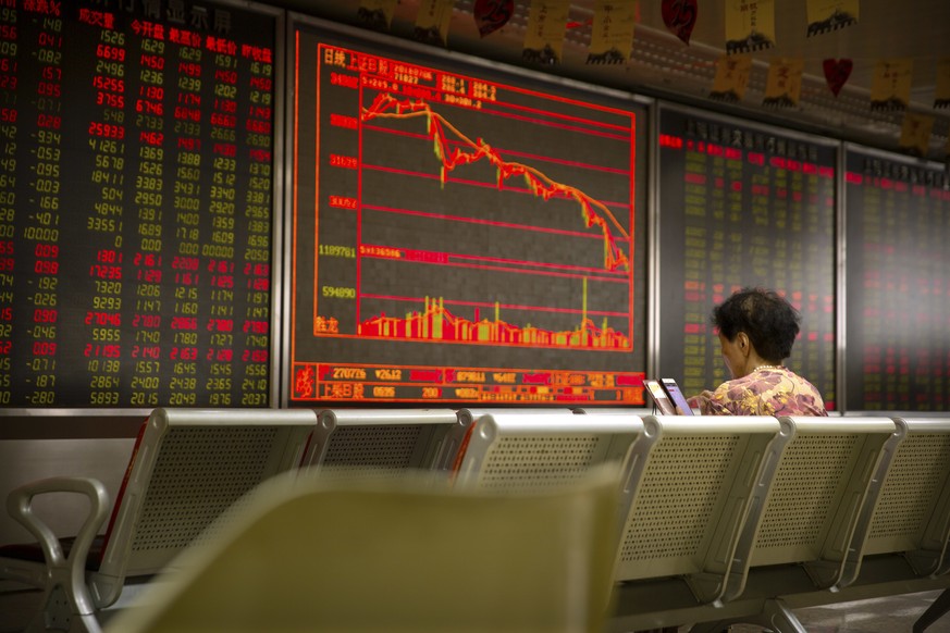 A Chinese investor uses her smartphone as she monitors stock prices at a brokerage house in Beijing, Friday, July 6, 2018. President Donald Trump made clear Thursday that U.S. tariffs against Chinese  ...