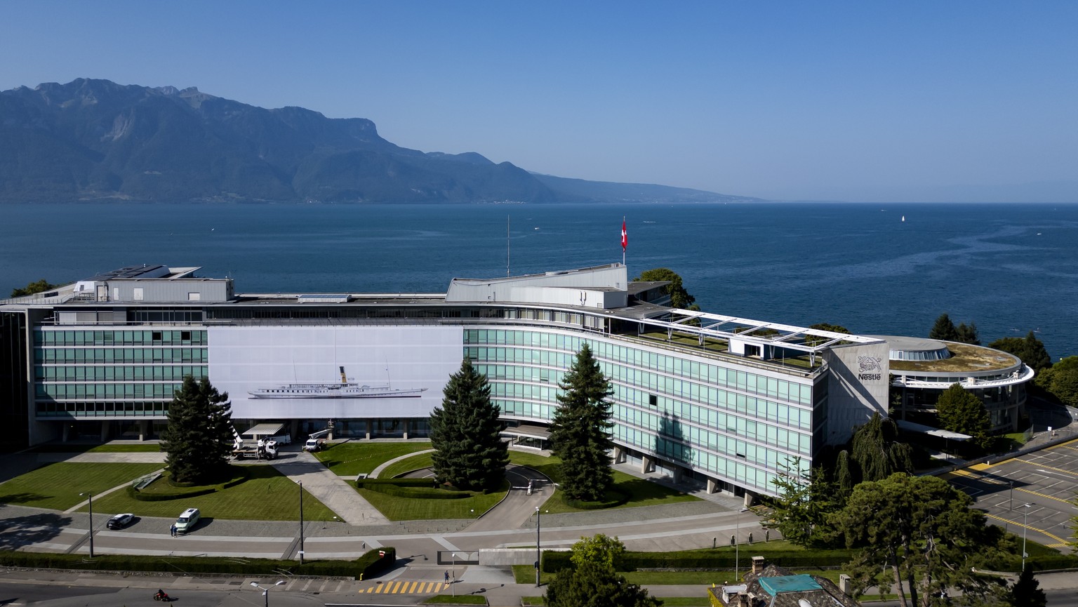 epa11562646 A drone picture shows workers hanging a giant photograph titled &#039;Belle epoque&#039; by Swiss artist Vincent Jendly, showing the &#039;La Suisse&#039; steam boat, on the facade of the  ...