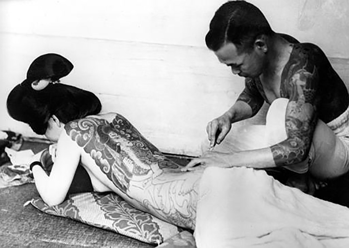 An unidentified Japanese tattoo artist works on a woman's backside in Tokyo, Japan, on June 22, 1937. (AP Photo)
