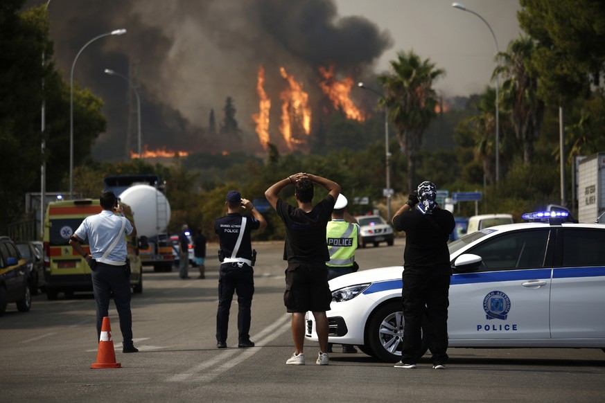 epaselect epa09392004 Citizens and police officers watch the wildfire burning at Varybobi, northeastern suburb of Athens, Greece, 03 August 2021. The wildfire that broke out in a forest in the Varybob ...