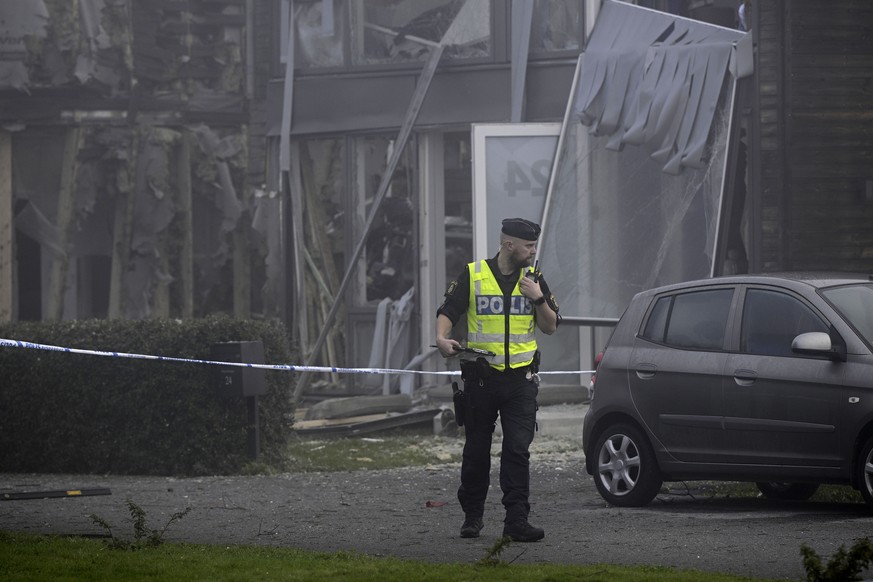 A police officer stands on the site of a powerful explosion that occurred early Thursday morning Sept. 28, 2023, in a housing area in Storvreta outside Uppsala, Sweden. A 25-year-old woman died in the ...