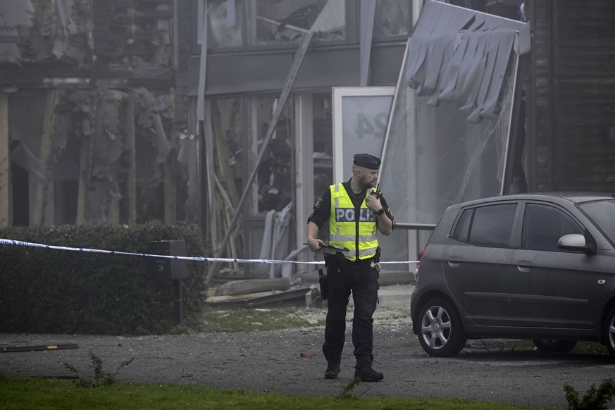 A police officer stands on the site of a powerful explosion that occurred early Thursday morning Sept. 28, 2023, in a housing area in Storvreta outside Uppsala, Sweden. A 25-year-old woman died in the ...