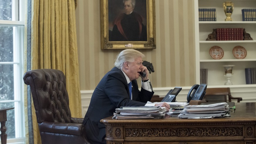 epaselect epa05757299 US President Donald J. Trump speaks on the phone with Chancellor of Germany Angela Merkel, in the Oval Office of the White House in Washington, DC, USA, 28 January 2017. Presiden ...