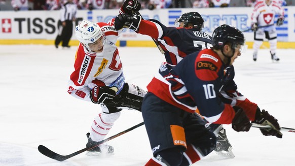 Reto Suri of Switzerland, left, fights for the puck with Lukas Kozak of Slovakia, during the ice hockey gold medal game (final) of the Arosa Challenge, on Saturday, December 19, 2015, in Arosa, Switze ...