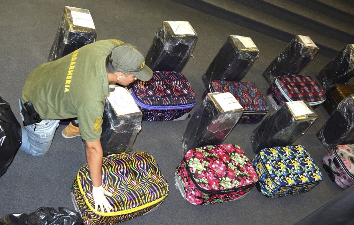 In this photo taken on Dec. 14, 2016, and released on Feb. 22, 2018, by the Argentine Security Ministry, a police officer guards suitcases that carried cocaine, that were found in an annex building of ...