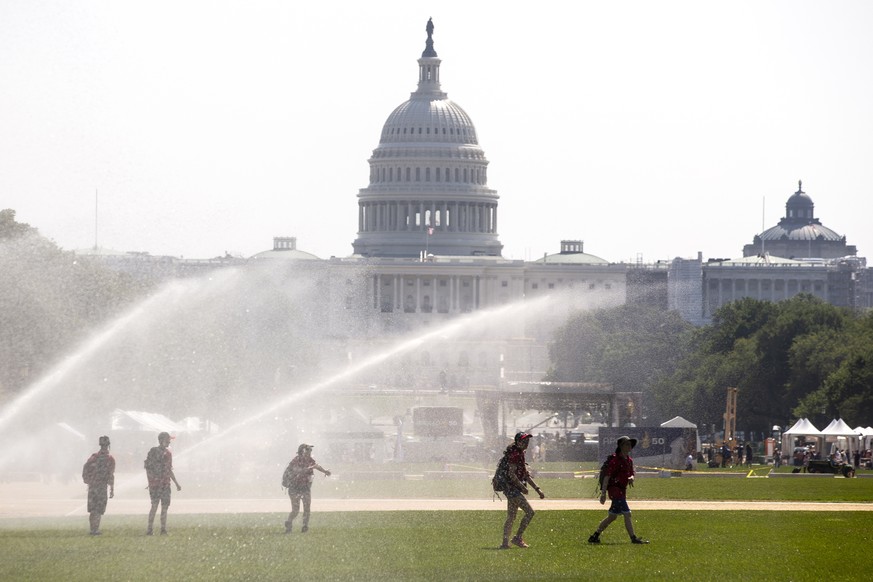 epa07727652 Youths walk under large sprinklers on the National Mall during an excessive heat watch in Washington, DC, USA, 19 July 2019. An excessive heat watch has been issued for the weekend in Wash ...