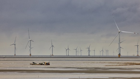 epa09470085 A boat sails past wind turbines in Rudong, Jiangsu province, China, 15 September 2021. The home base is where wind turbines and other offshore equipment are manufactured, maintained, and s ...