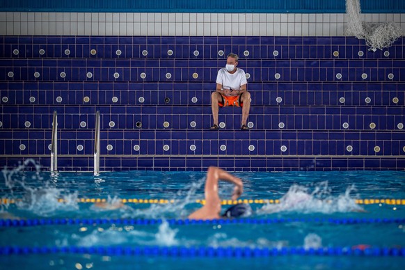 epa08443450 A lifeguard (back) wearing a protective face mask watches people in a swimming pool amid the ongoing coronavirus COVID-19 pandemic in Prague, Czech Republic, 25 May 2020. Swimming pools an ...