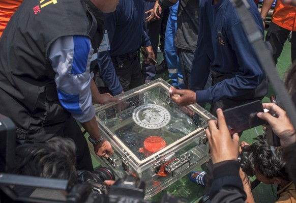 FILE - In this Thursday, Nov. 1, 2018, file photo, members of the National Transportation Safety Committee lift a box containing the flight data recorder from a crashed Lion Air jet onboard a rescue s ...